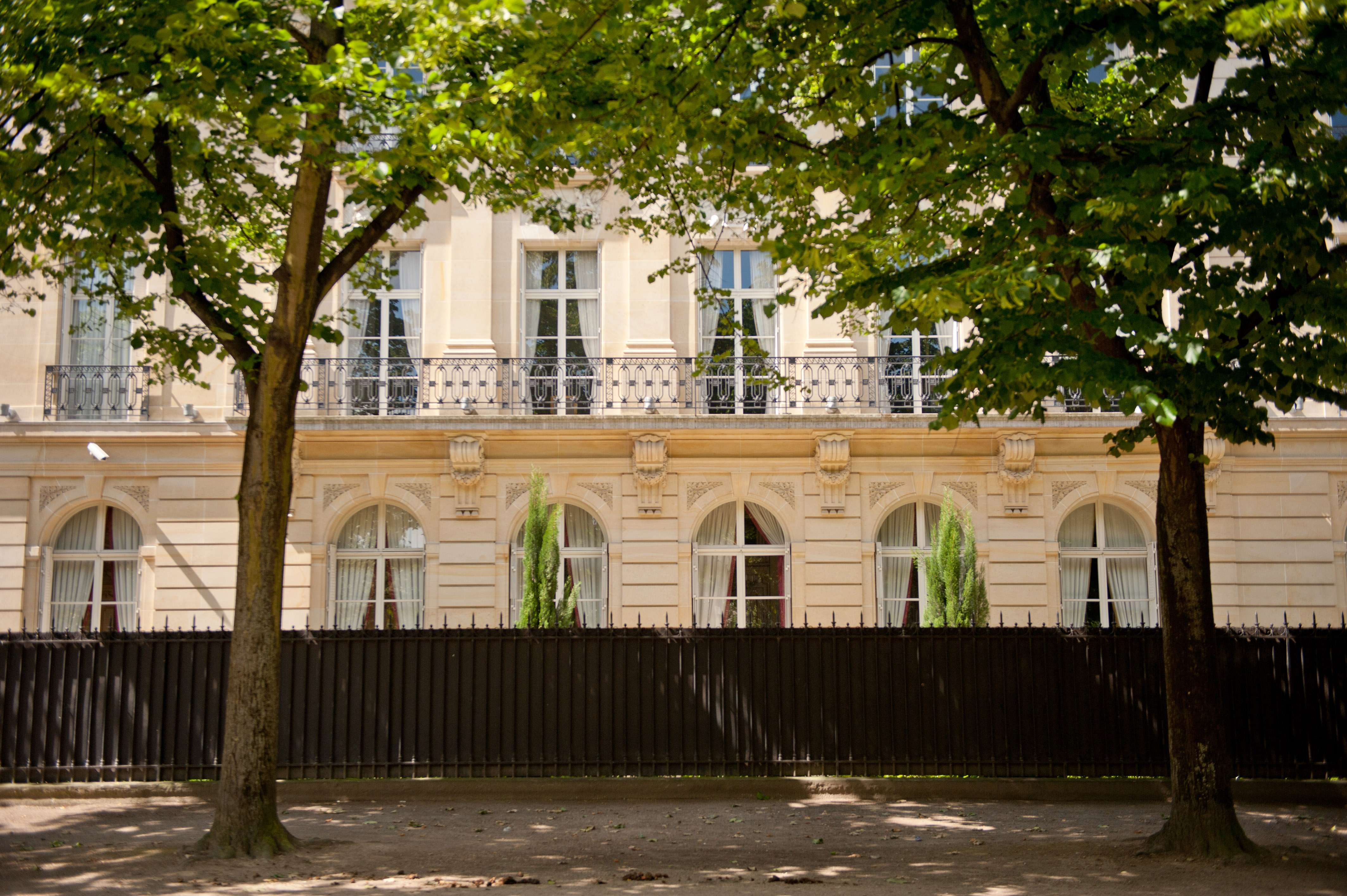 Au pied du Champ de Mars, un immeuble en pierre de taille, avec ses grilles en métal noir et arbre devant 