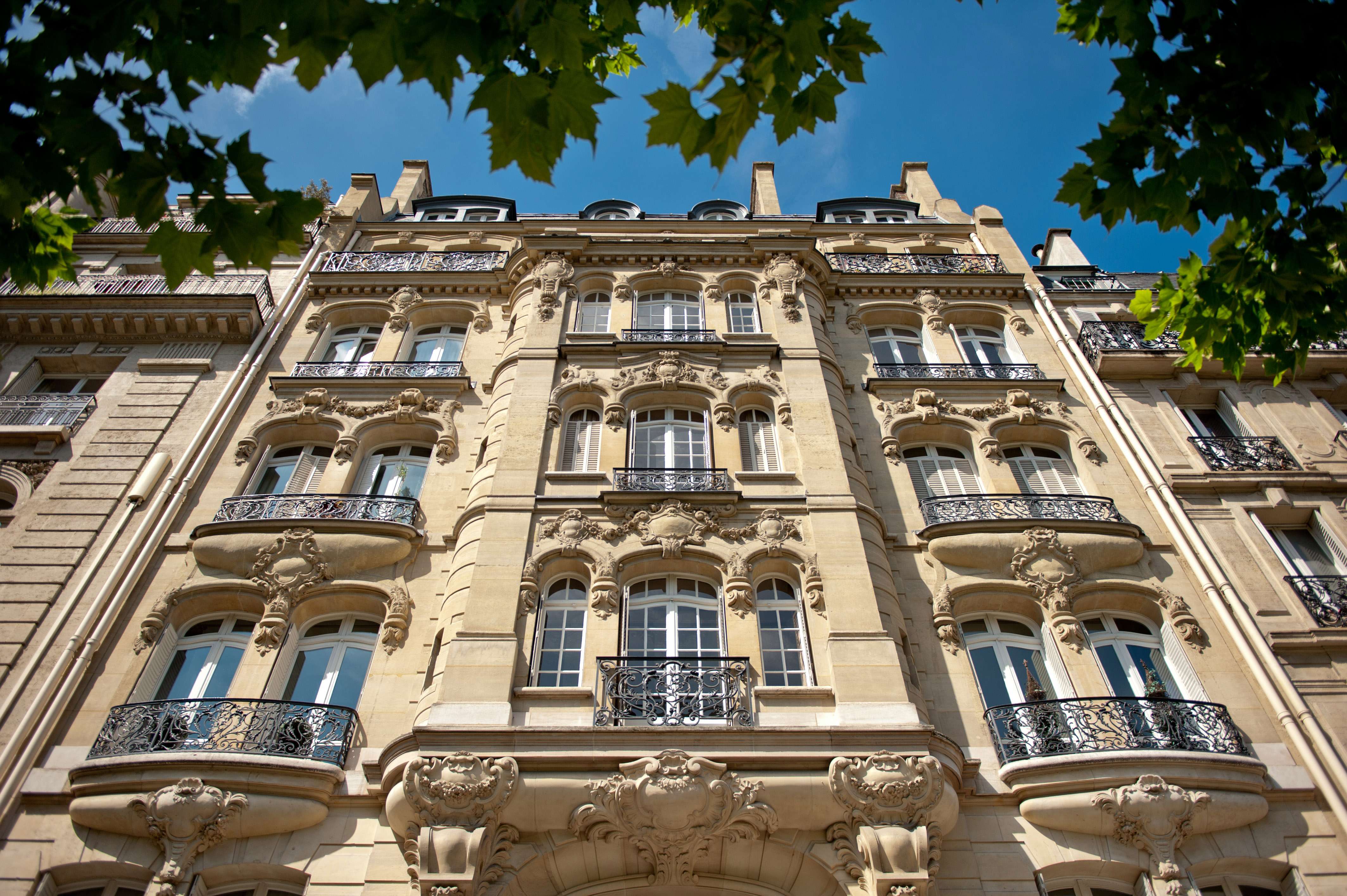 Façade d'un immeuble en pierre de taille, avec des arbres devant en bordure du champ de mars à paris