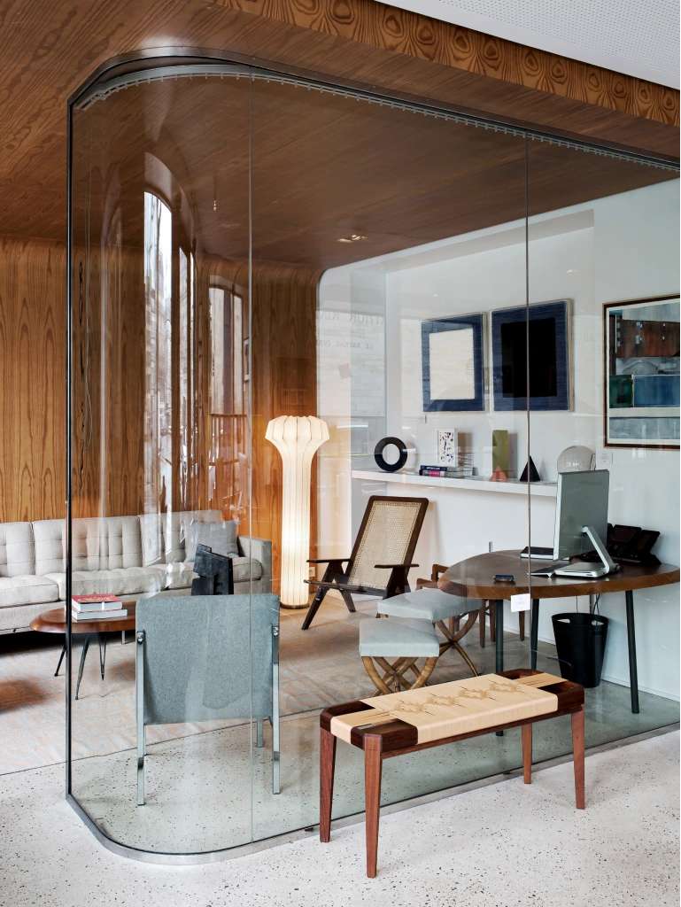 Bureau chaleureux avec des matériaux en bois, grande vitre arrondie, tapis élégant et tableaux accrochés aux murs