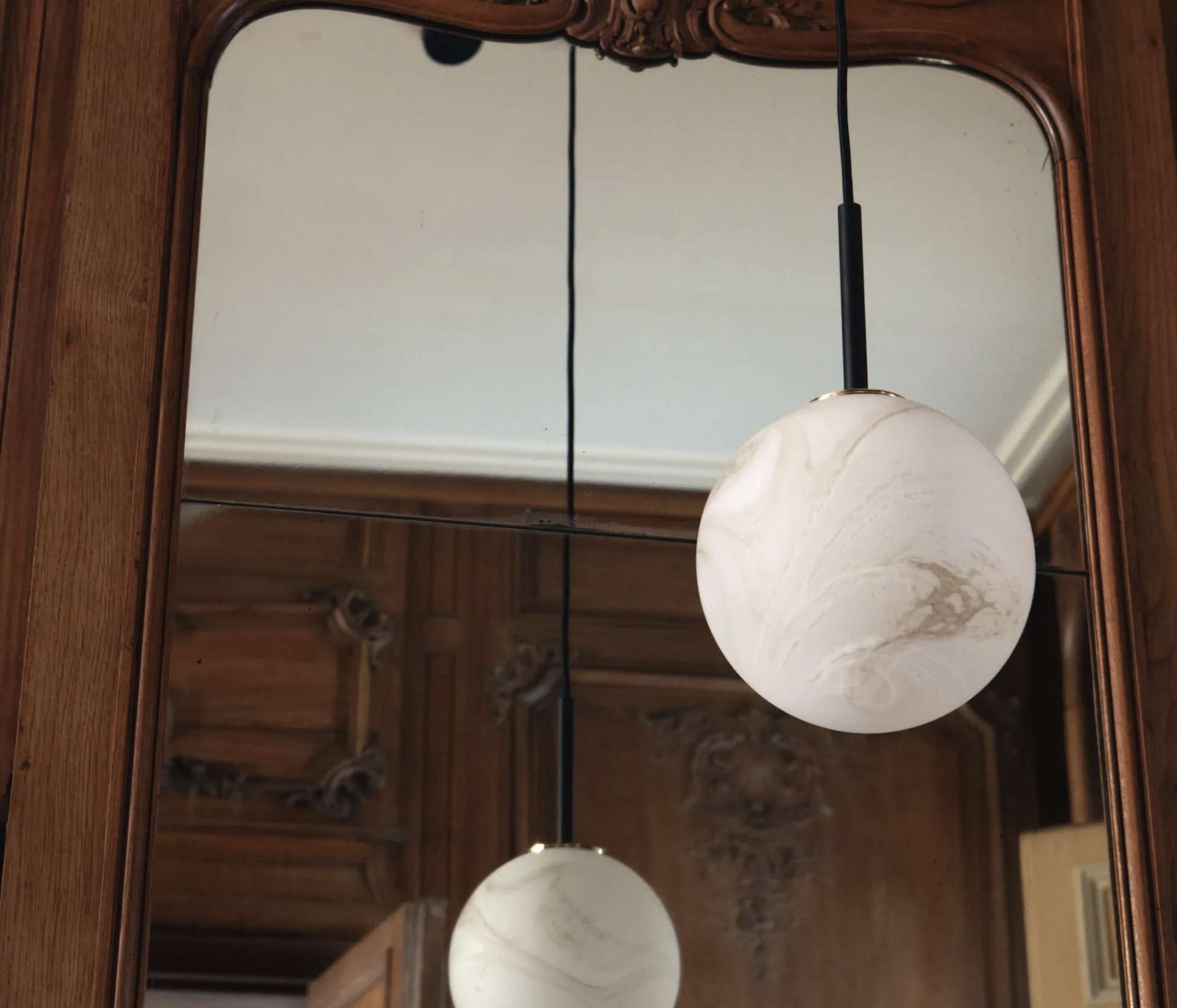 Suspension boule effet matière qui se reflète dans un grand miroir aux moulures