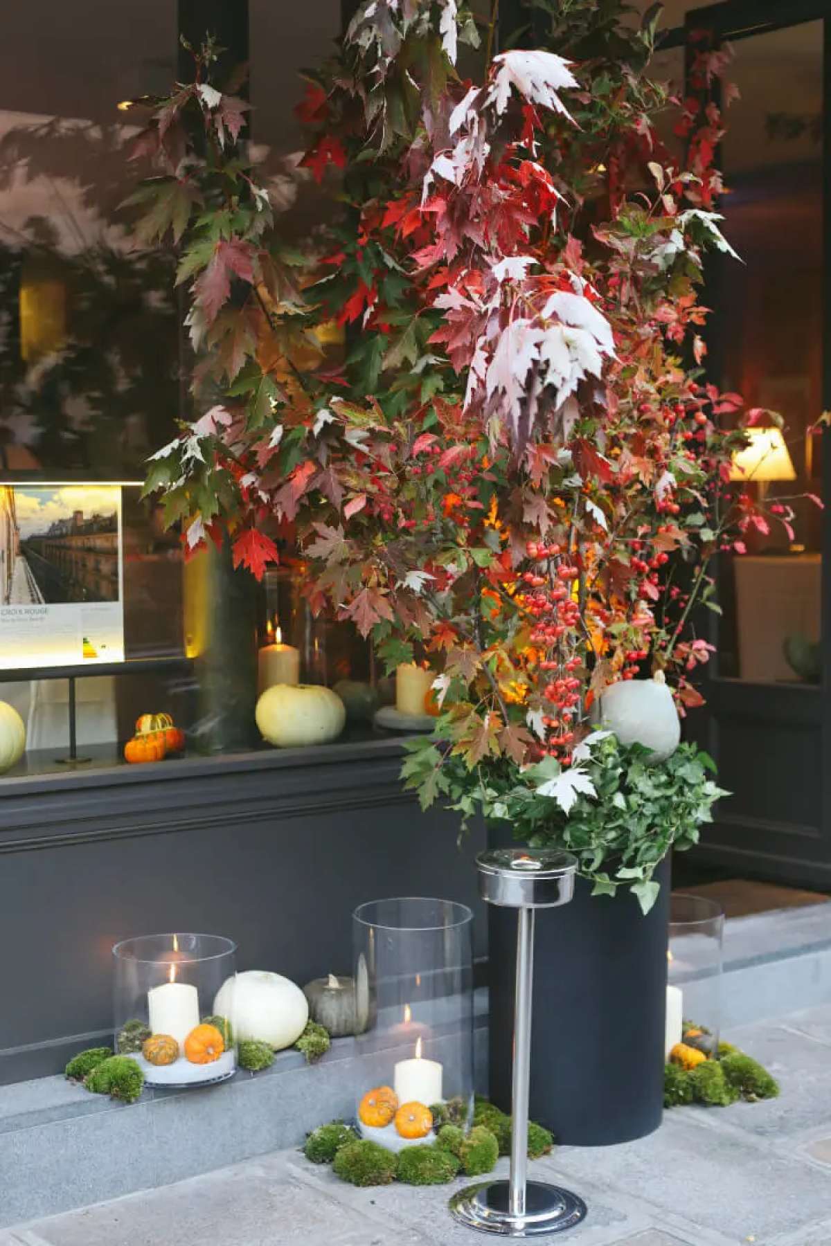 Vitrine de l'agence Varenne décorée avec des bougies et des végétaux d'automne, ornant également le trottoir