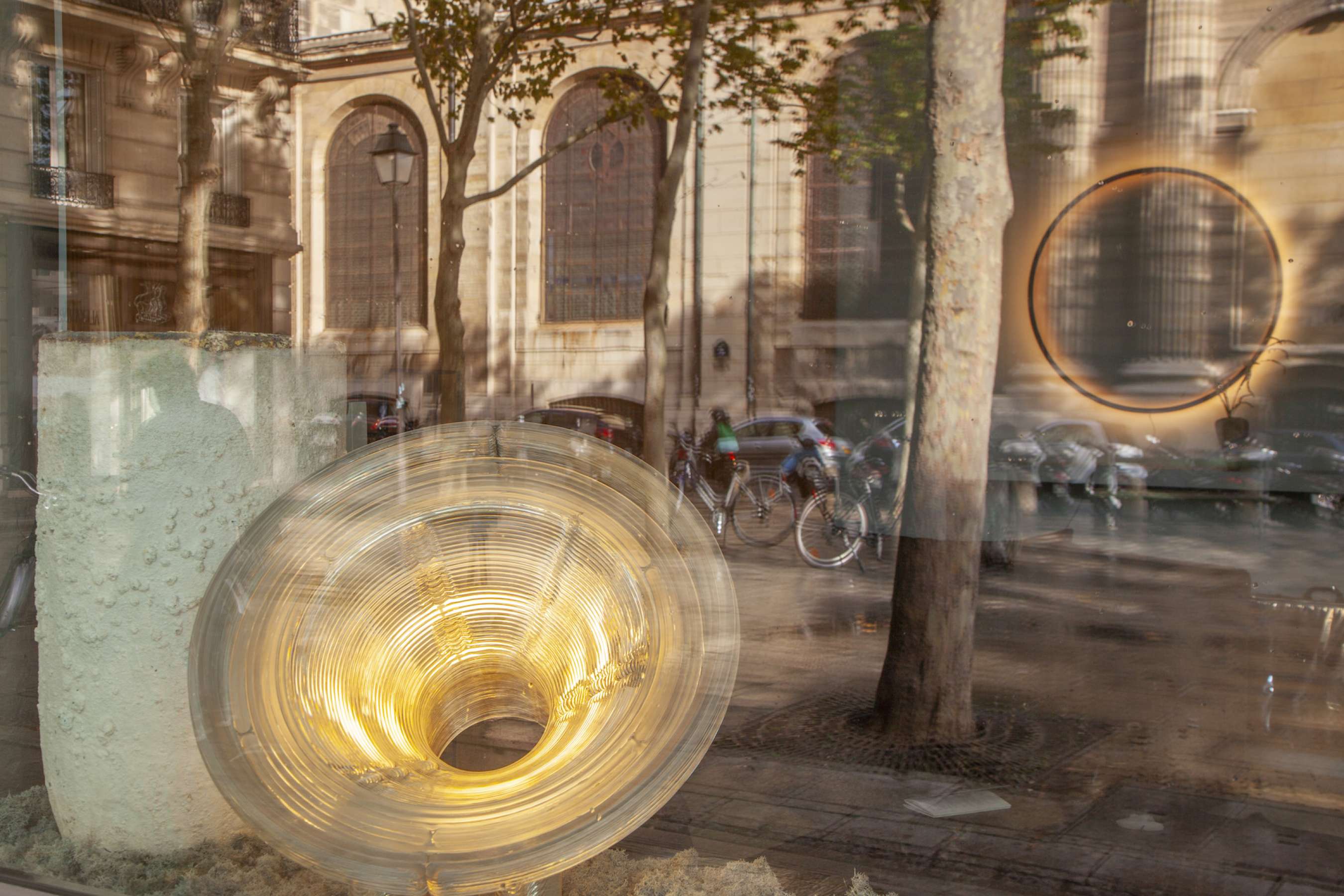 Vitrine avec lumières installées par Laurence Simoncini Décoration, on voit se refléter l'église saint sulpice à paris et les vélos et voitures garés